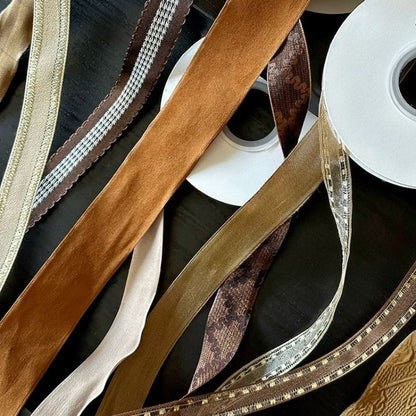Nine colors of vintage wired ribbon with satin gingham and stitched varieties fanned across surface in ivory tan caramel coffee chocolate and espresso tones — Sivonna earth tone craft ribbon