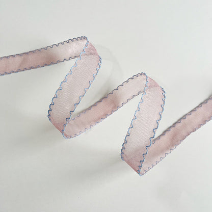 Scallop edge sheer ribbon rolls in pink sage blue and floral print arranged on antique plate with grape hyacinth and ranunculus — Sivonna bridal craft ribbon collection